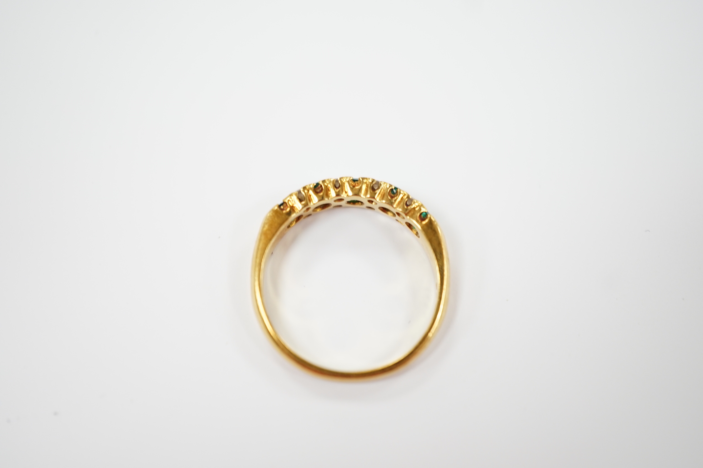 A modern 18ct gold and five stone emerald set half hoop ring, with diamond chip spacers, size K/L, gross weight 3 grams.